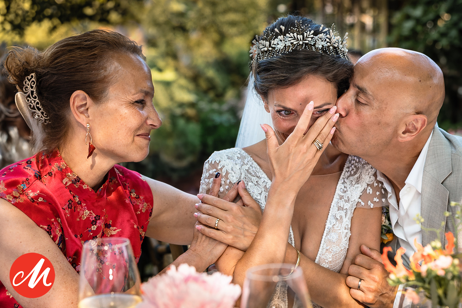 Emotionele close-up van een bruid die een traan wegveegt terwijl ze wordt gekust door een familielid tijdens het diner.