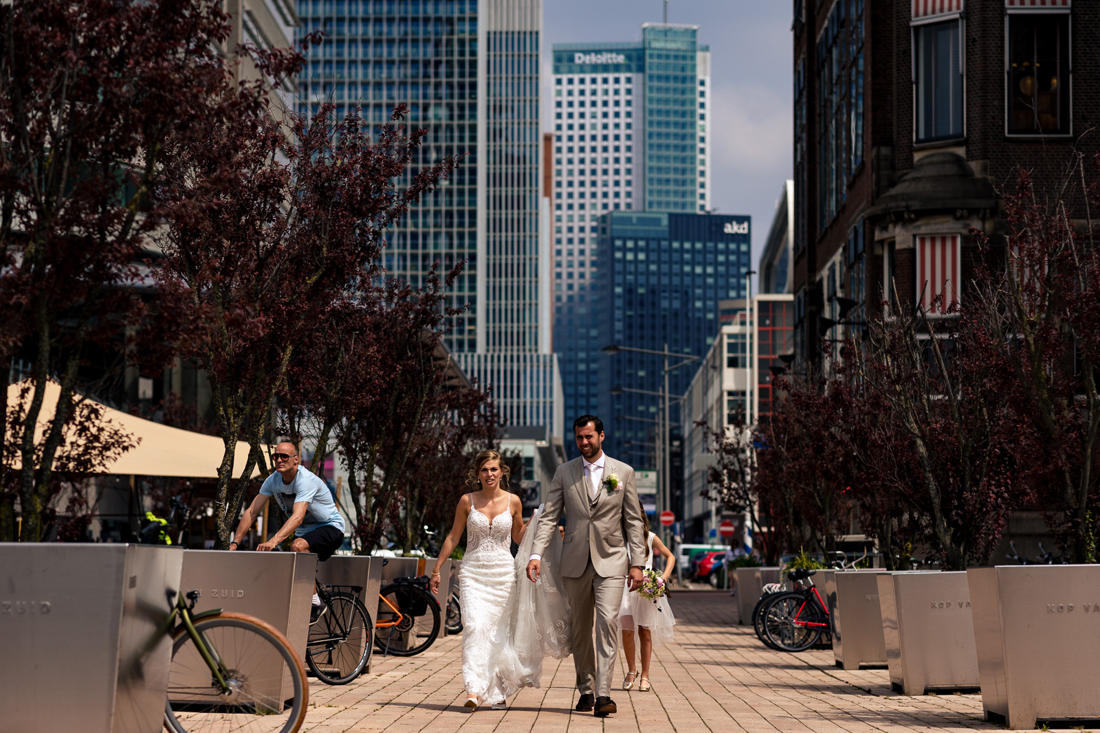 bruidspaar loopt bij Hotel New York te Rotterdam met skyline op de achtergrond