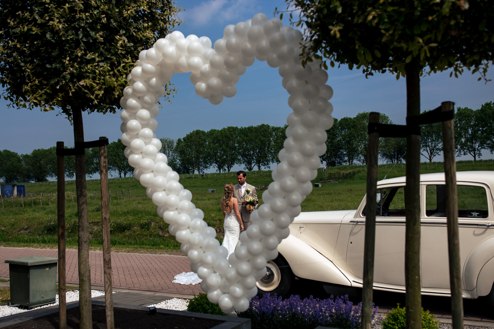 First look bruidspaar met ballonnen hart in de voortuin