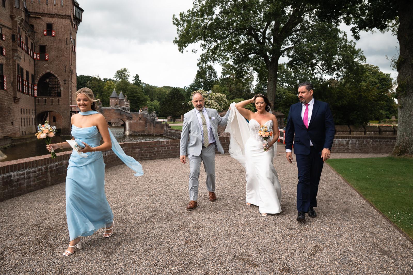 Bruid Nadine loopt met haar familie naar de kapel bij kasteel de haar