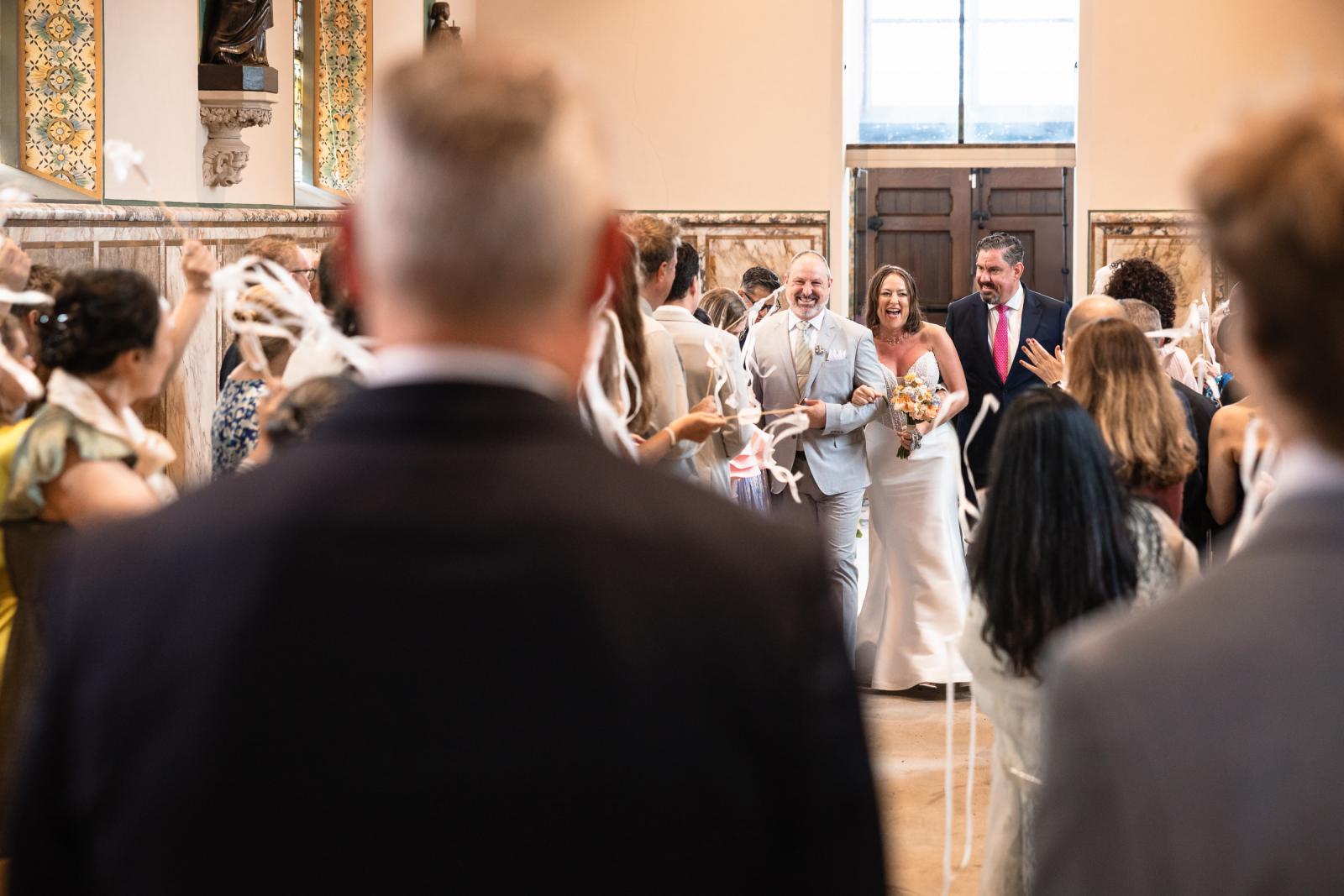 Bruid Nadine loopt arm in arm door het gangpad van de kapel tijdens de ceremonie