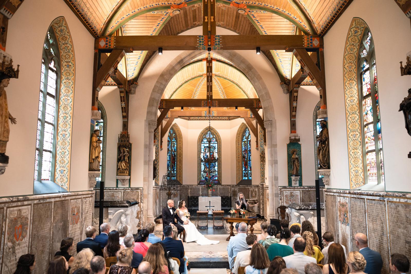 Bruid Nadine en bruidegom Mike luisteren naar de speech tijdens de ceremonie bij Kasteel de Haar