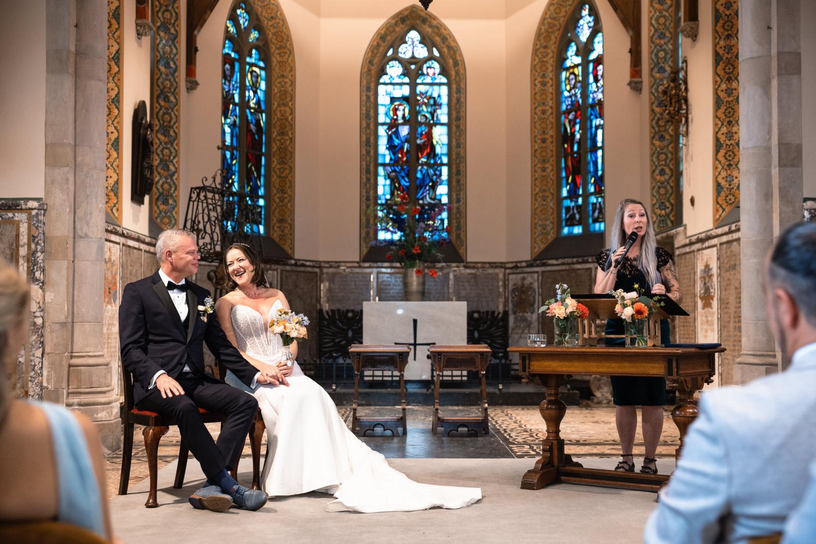 Bruidspaar kijkt en lacht naar elkaar tijdens de ceremonie in de kapel bij Kasteel de Haar