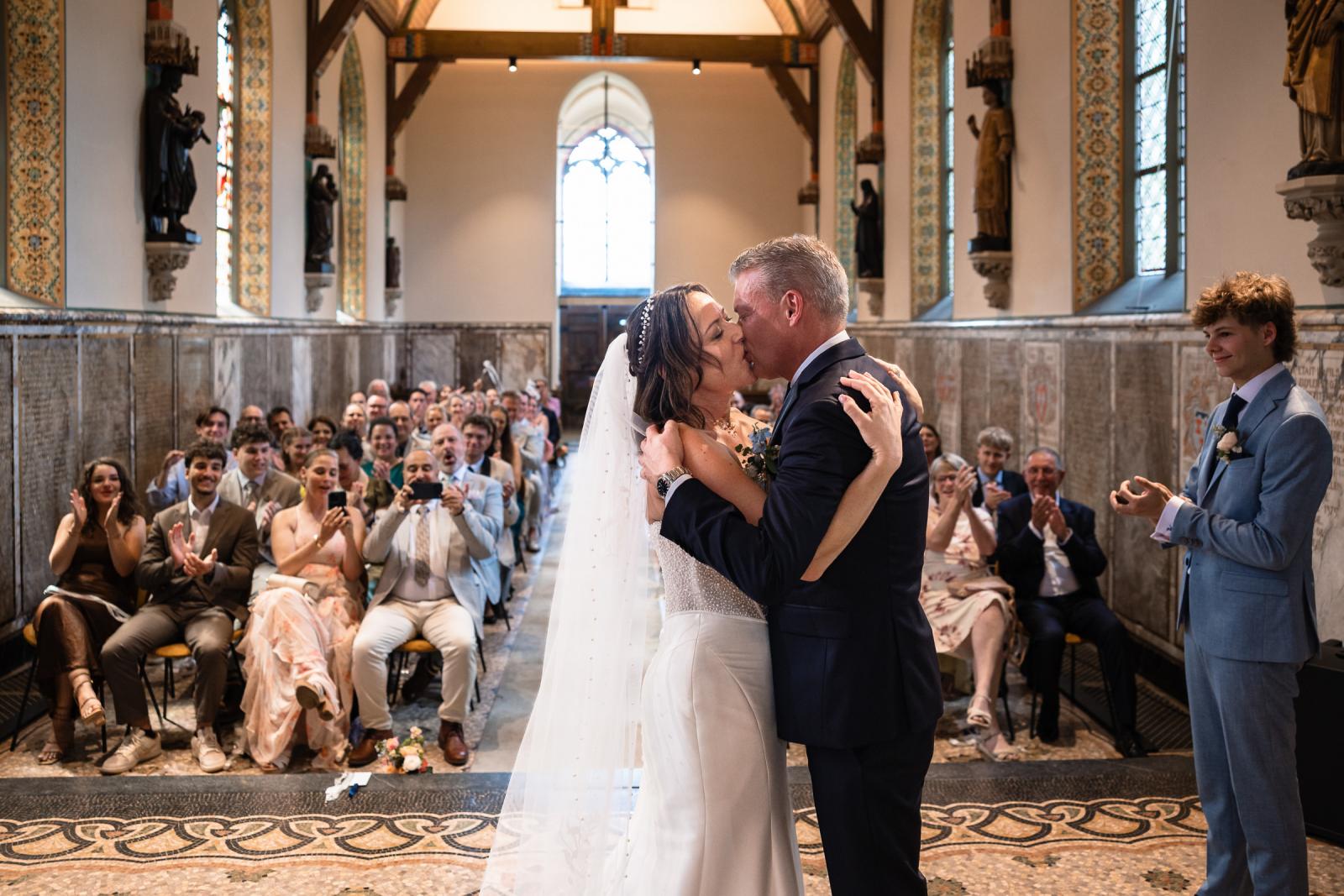 Bruid Nadine en bruidegom Mike delen hun eerste kus als getrouwd stel in de kapel