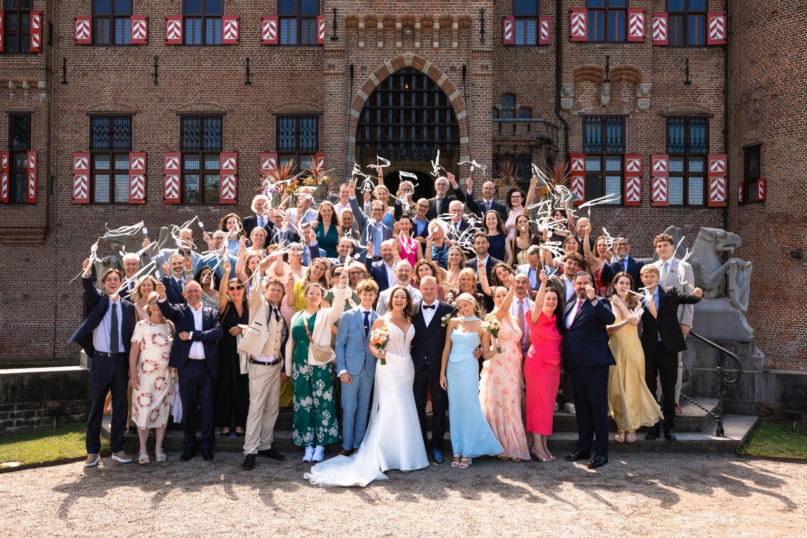 Grote groepsfoto van het bruidspaar Mike en Nadine met al hun bruidsgasten op de bordestrap van Kasteel de Haar.