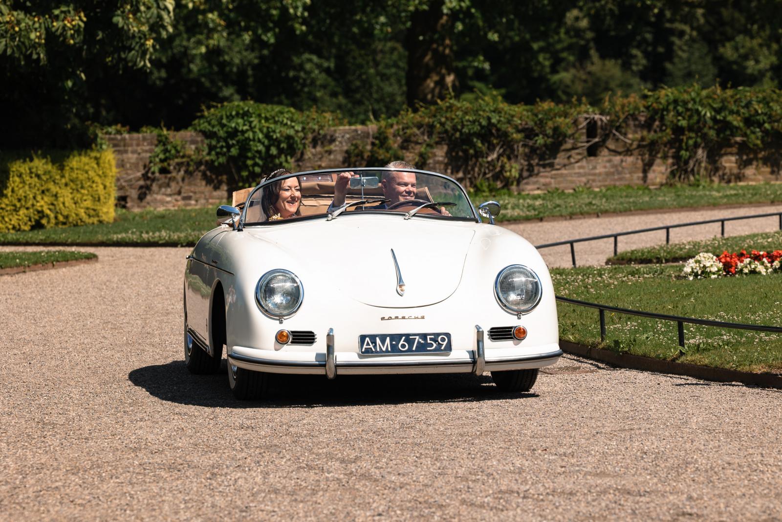 Mike en Nadine rijden lachend in hun witte vintage Porsche cabrio over het landgoed van Kasteel de Haar.