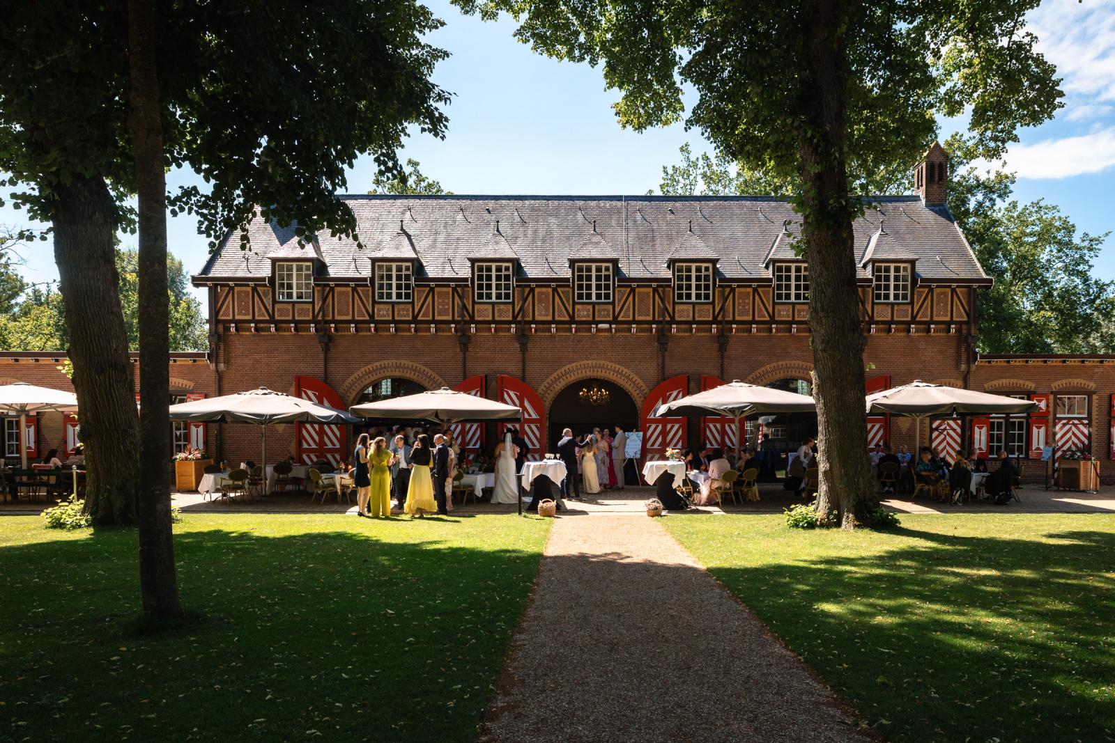 Overzichtsfoto van het zonnige terras van Koets his Kasteel de Haar waar bruidsgasten genieten van de borrel.