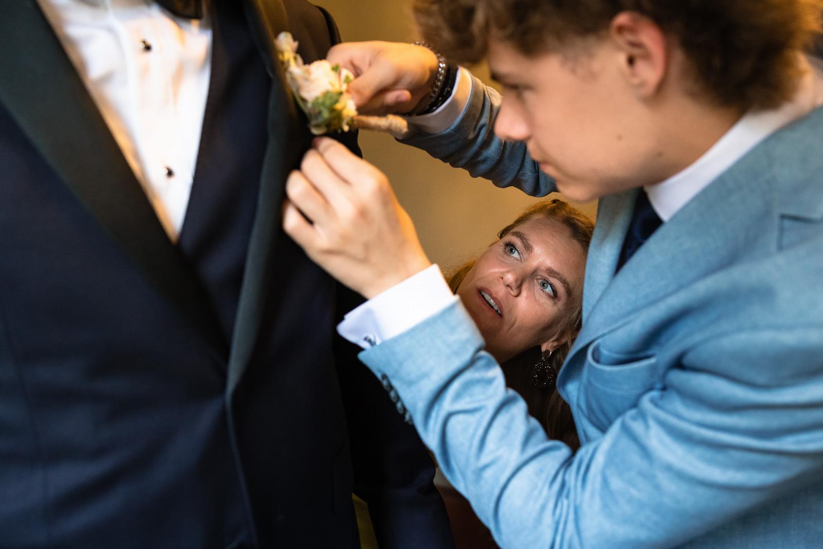 Zoon spelt corsage op bij het pak van bruidegom Mike tijdens de voorbereidingen
