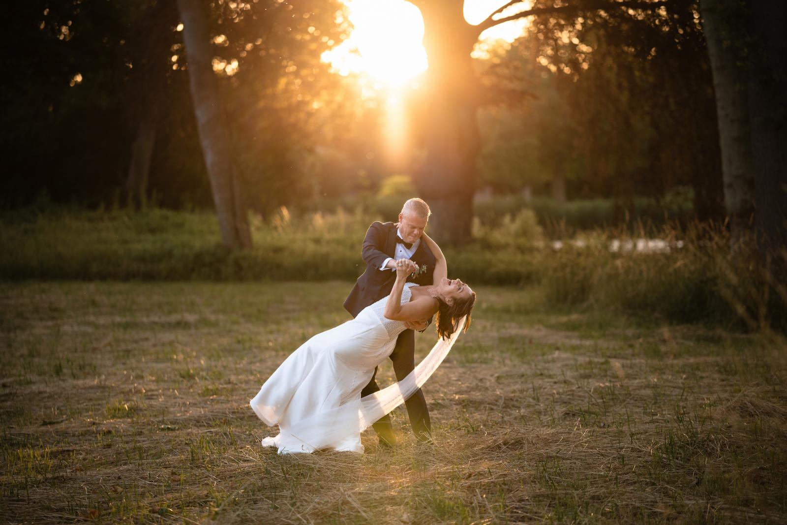 Bruidegom Mike tilt bruid Nadine speels op voor een dip tijdens de shoot bij zonsondergang.