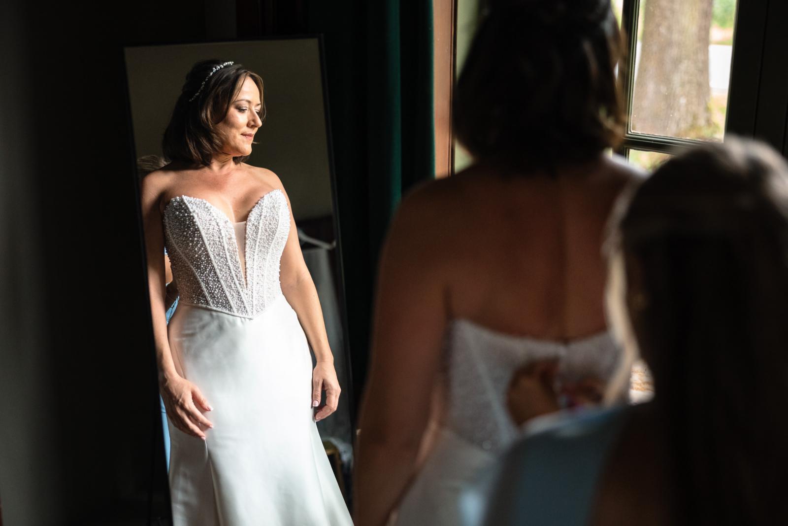 Bruid Nadine kijkt in de spiegel naar haar trouwjurk met parels bij Kasteel de Haar