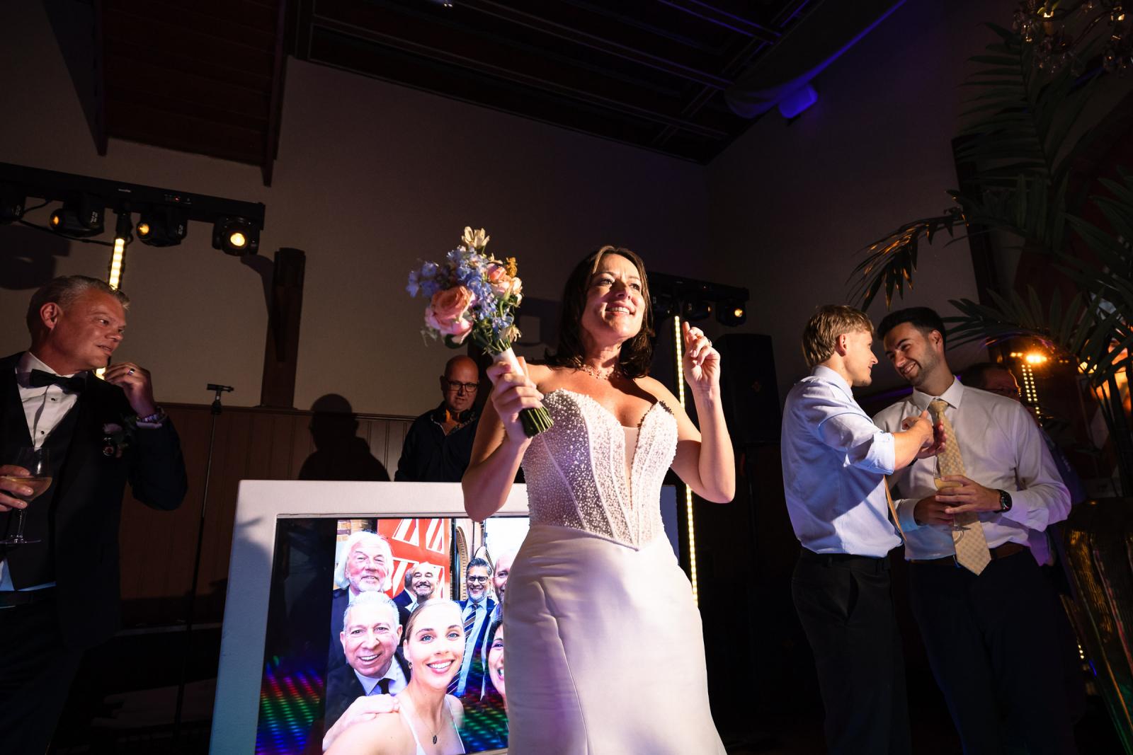 Bruid Nadine staat klaar op de LED-dansvloer om haar trouwboeket achterwaarts naar de gasten te gooien.