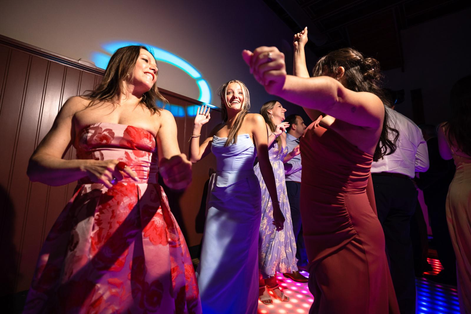 Enthousiaste vrouwelijke gasten dansen vol energie op de verlichte dansvloer tijdens het avondfeest.