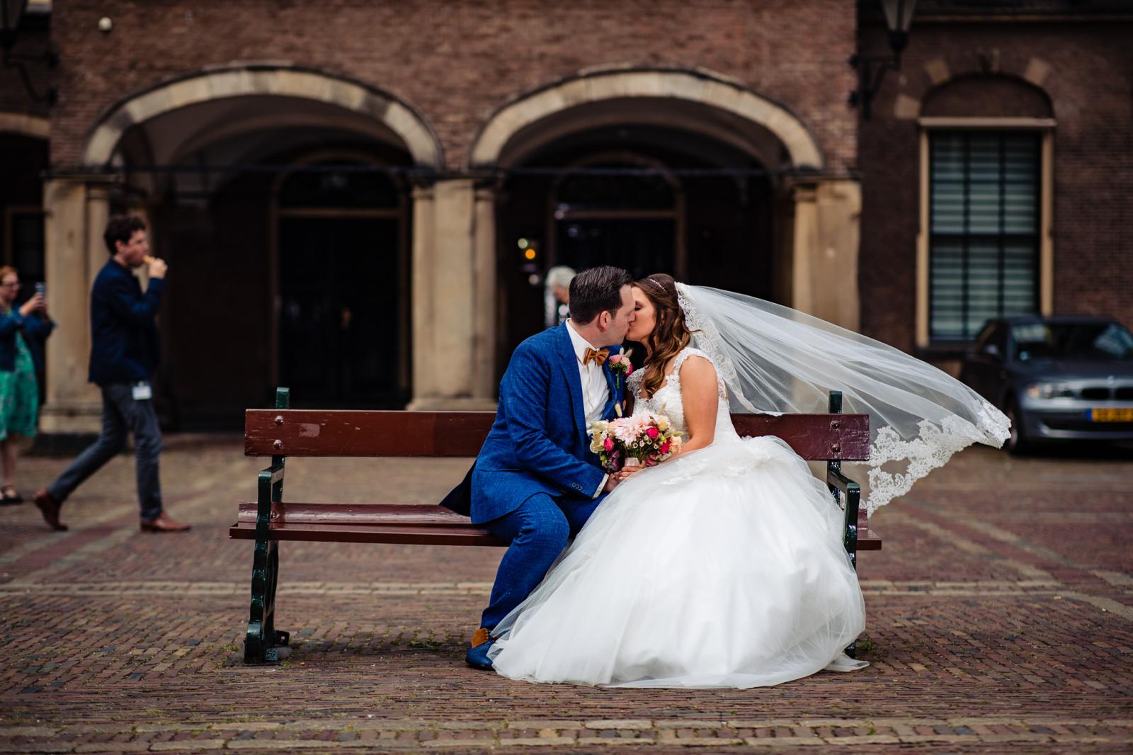 bruidspaar kust op bankje binnenhof