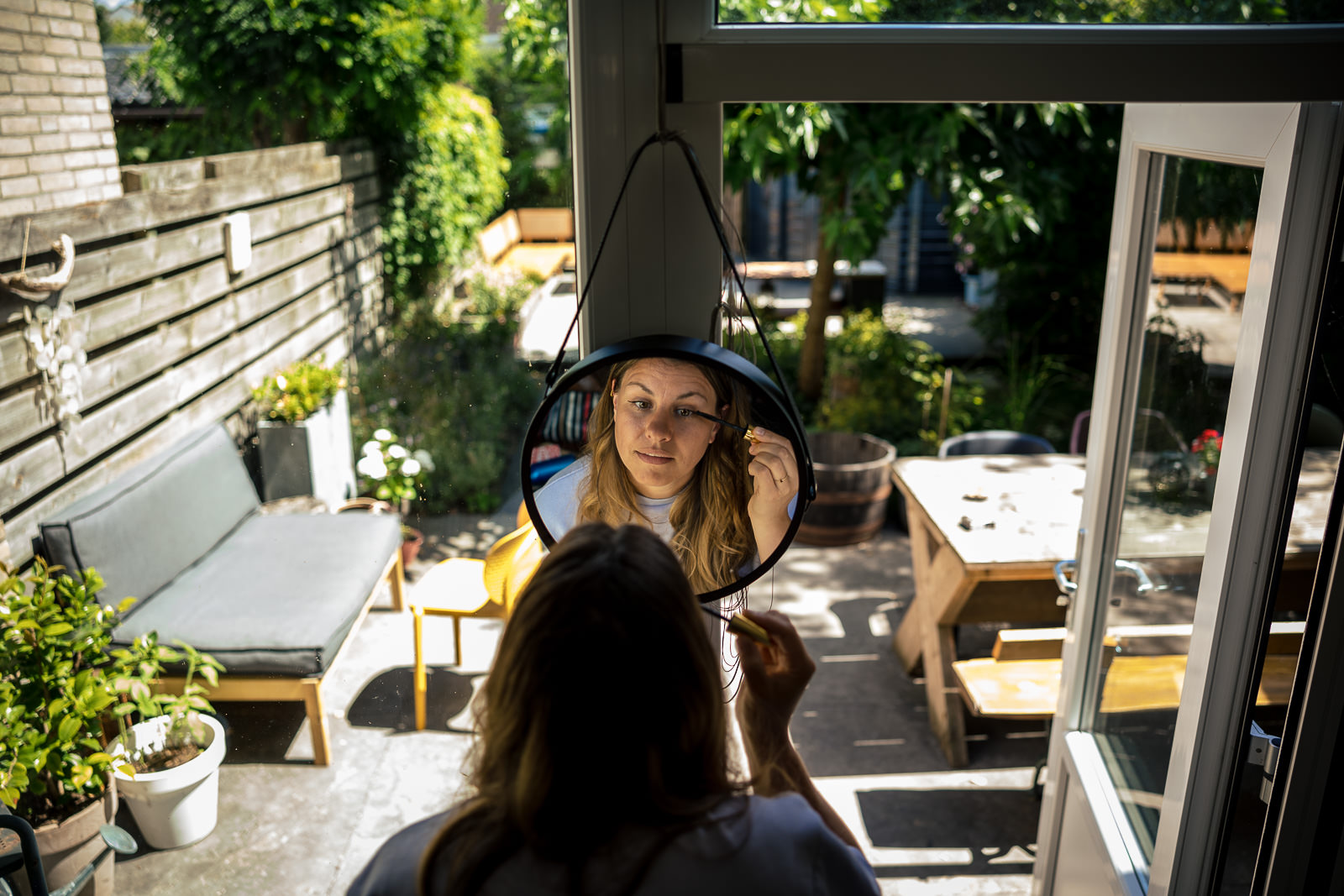 Bruid doet zelf haar make-up op tijdens de voorbereiding door Trouwfotograaf Het Koetshuis in Bennekom