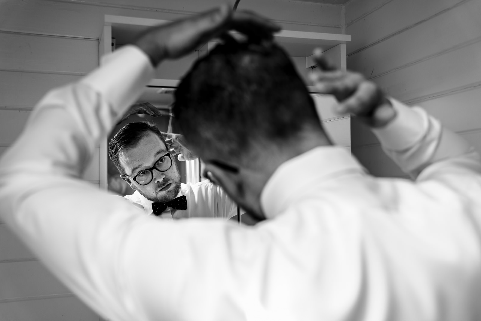 Bruidegom doet z'n haren in de badkamer spiegel door Trouwfotograaf Het Koetshuis in Bennekom