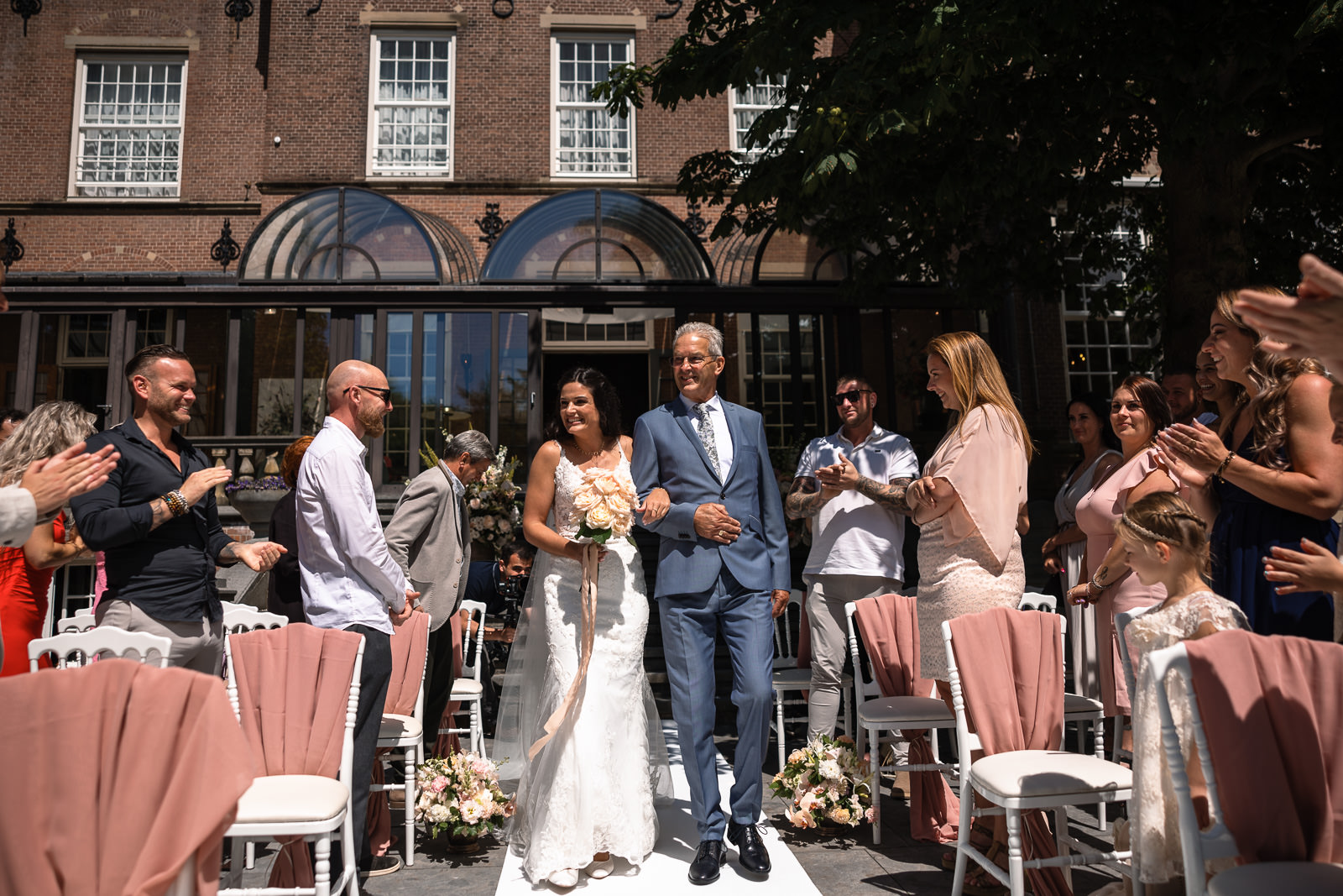 Bruid komt met vader oplopen voor de ceremonie bij kasteel de Wittenburg in Wassenaar