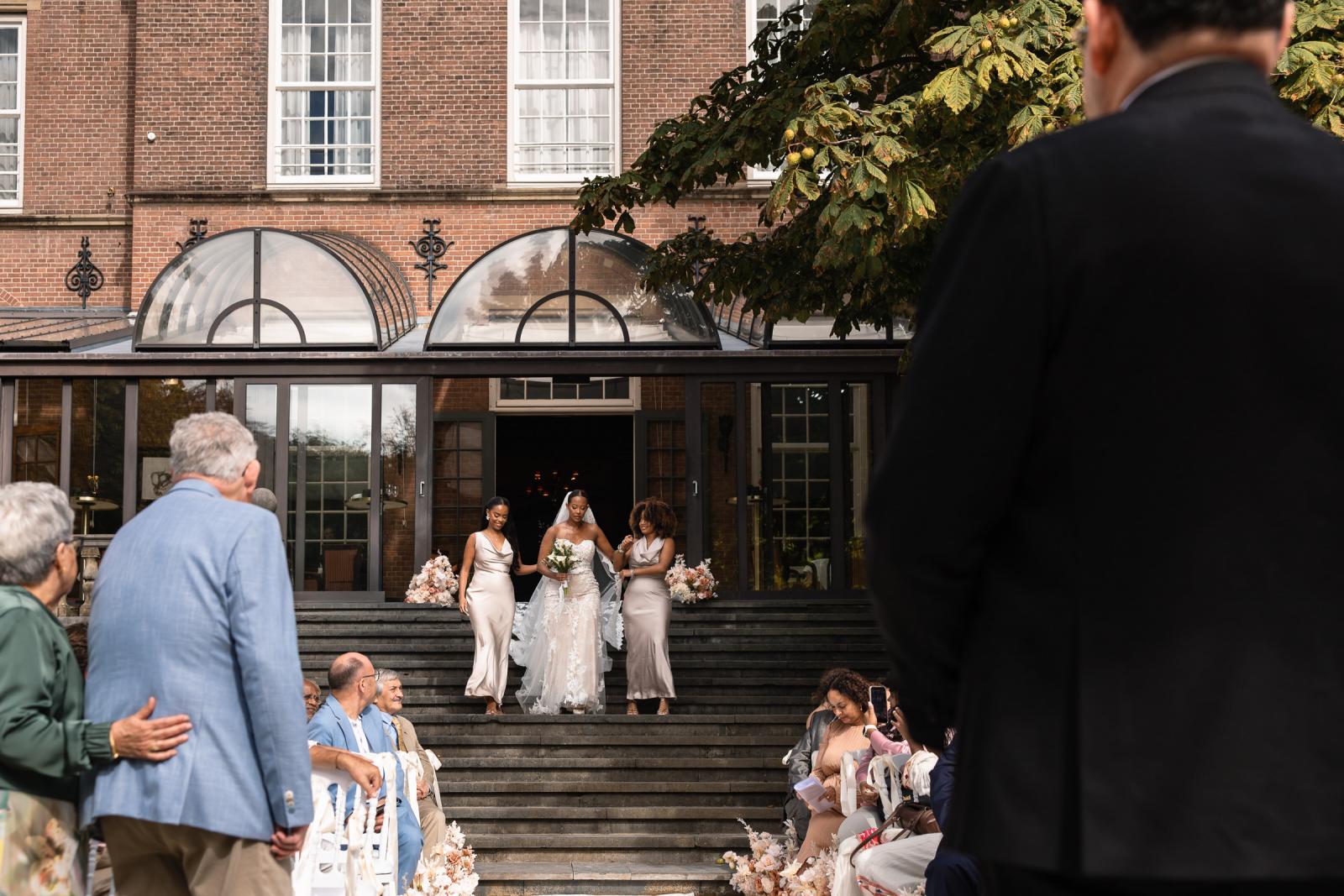 Bruid Tigist daalt de kasteeltrap af naar de ceremonie, omringd door haar bruidsmeisjes.