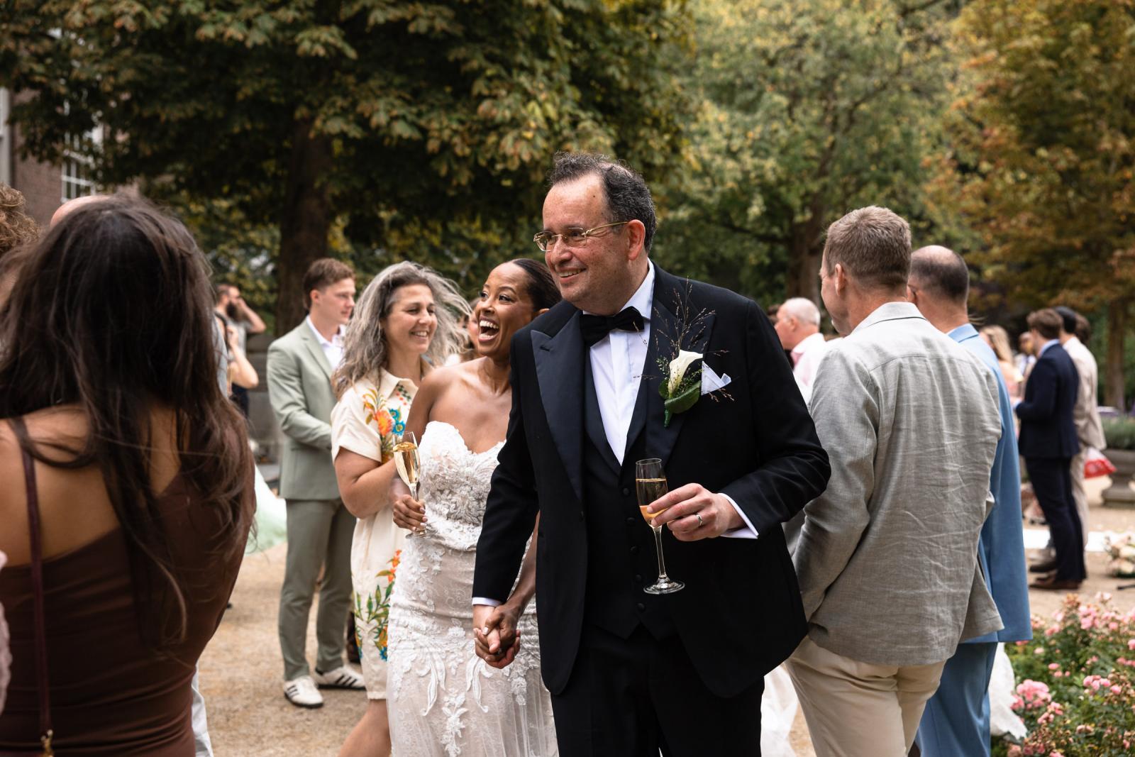 Ronald en Tigist lopen hand in hand en stralen van geluk tussen de gasten tijdens de receptie.