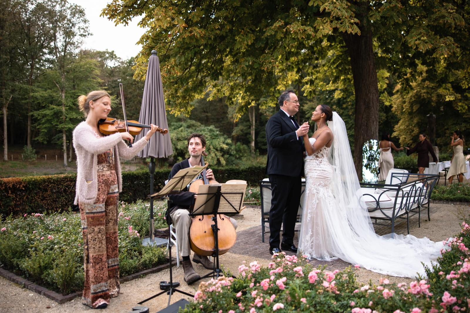 Livemuziek met viool en cello gespeeld door muzikanten in de kasteeltuin terwijl het bruidspaar danst.