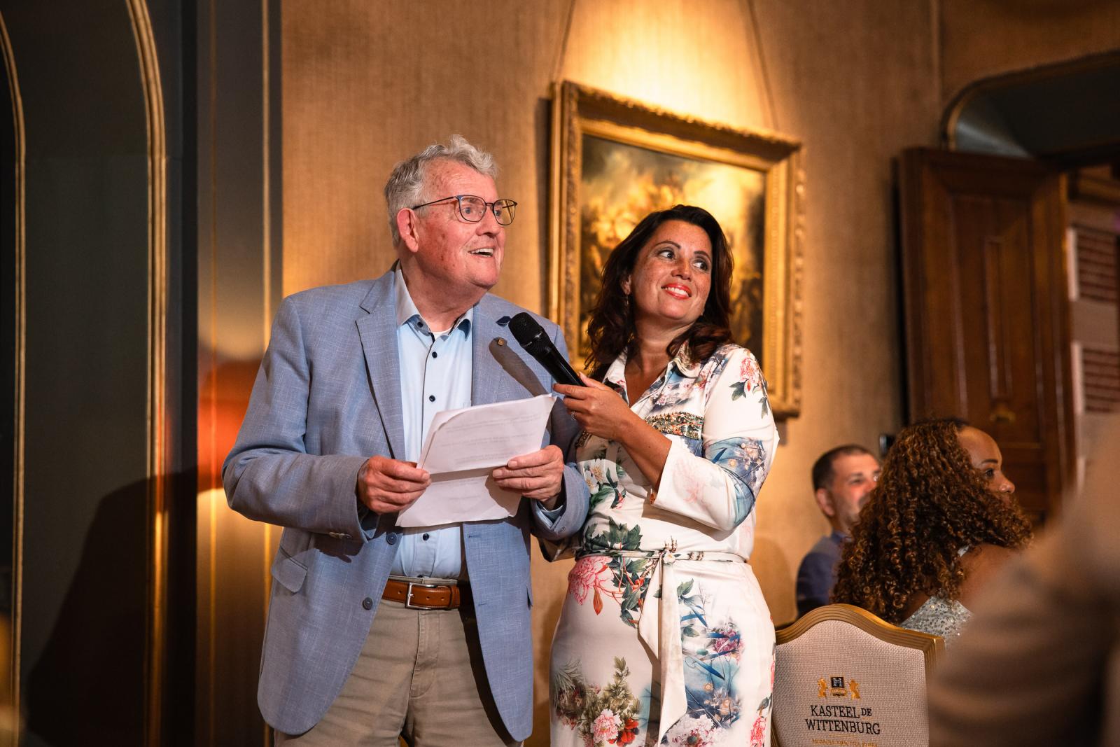 Gasten houden een persoonlijke toespraak met microfoon tijdens het diner in de zaal.