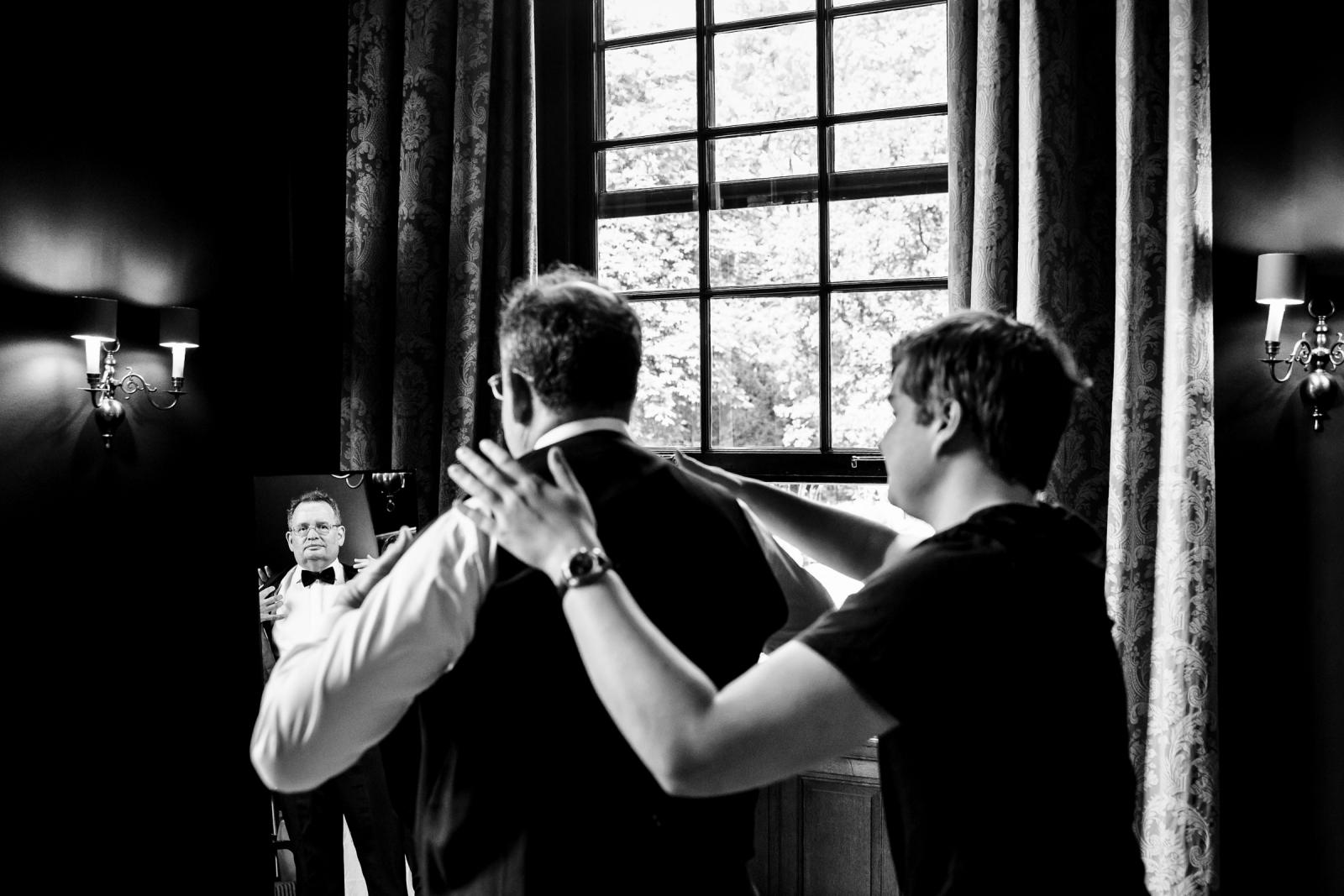Bruidegom Ronald krijgt hulp bij het aantrekken van zijn stijlvolle tuxedo voor de kasteelbruiloft.