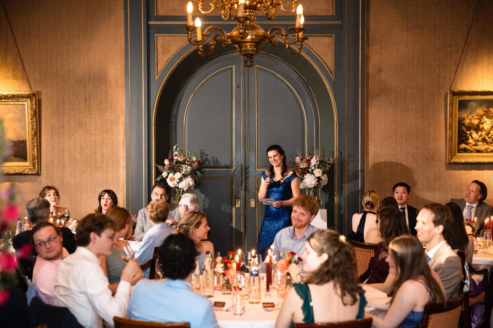 Gast spreekt tijdens diner onder kroonluchter, bruiloft Kasteel de Wittenburg Wassenaar