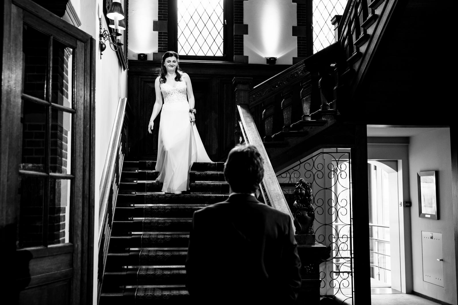 First look op de trap: bruid loopt naar beneden in Kasteel de Wittenburg, Wassenaar
