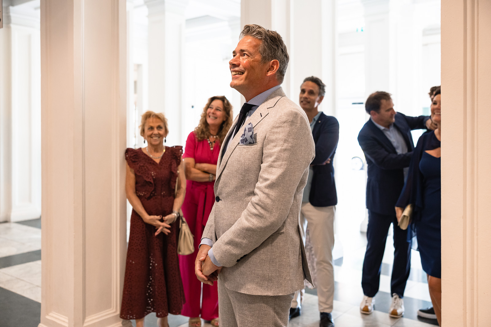 Een stralende bruidegom staat zijn bruid op te wachten bij de first look bij Wereld Museum Rotterdam