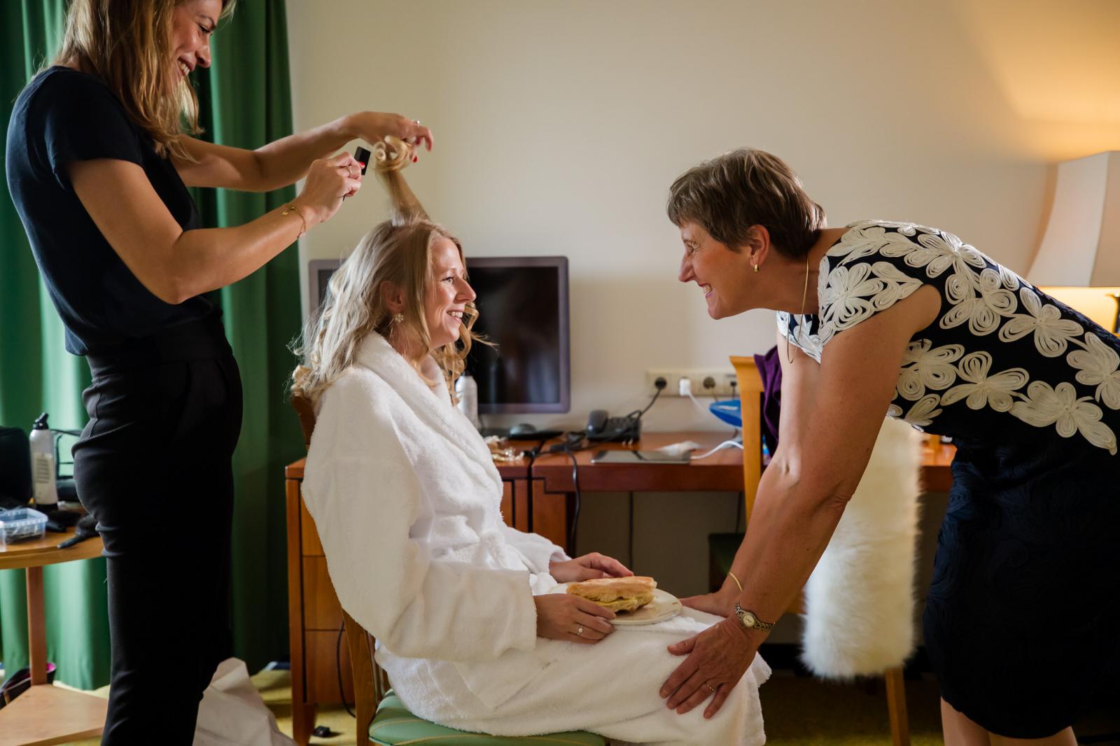 Bruidskapsel en make-up wordt aangebracht bij bruid