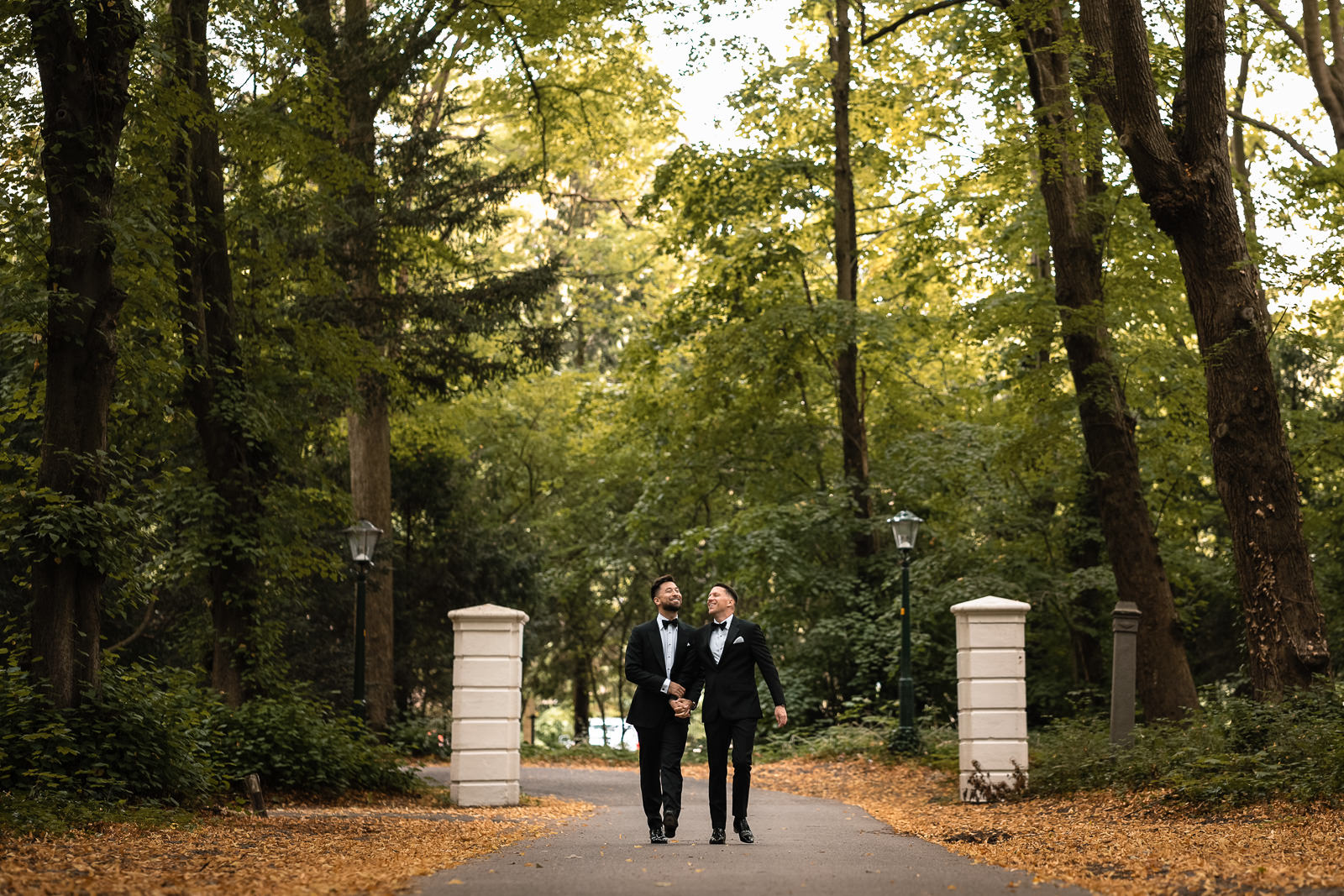 Same sex wedding couple walking down the castle driveway