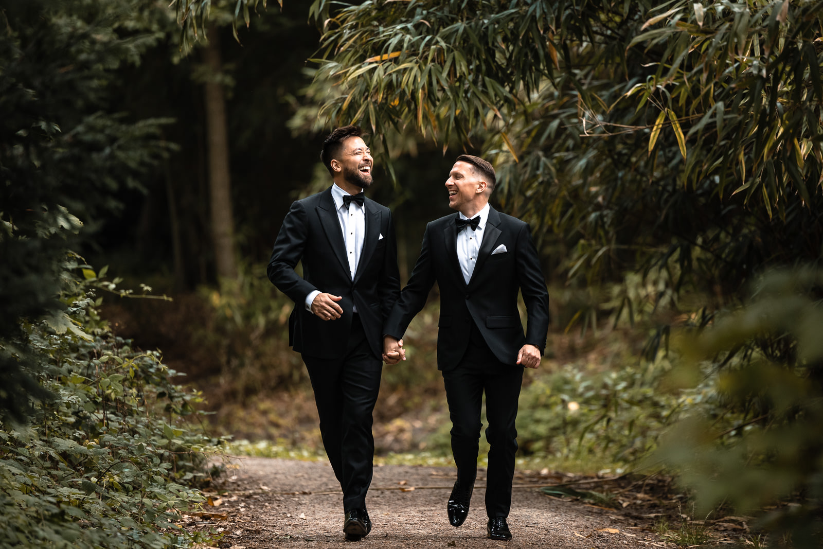 Two grooms frolicking together during their wedding shoot