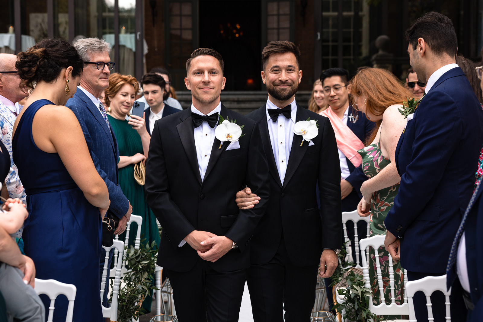 Two grooms walking down the isle together during same sex wedding