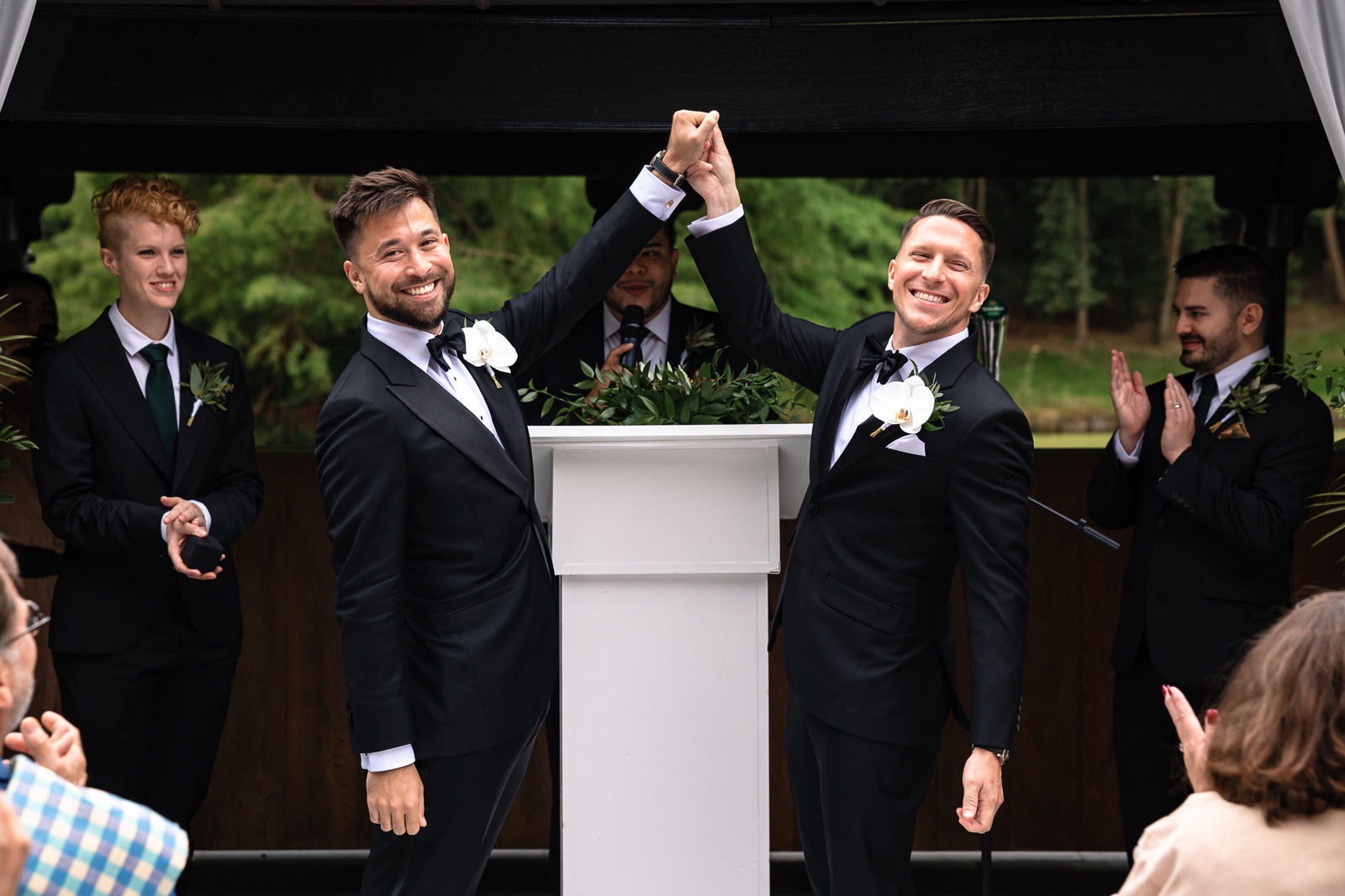 Two grooms celebrating their marriage with a cheer at a castle wedding