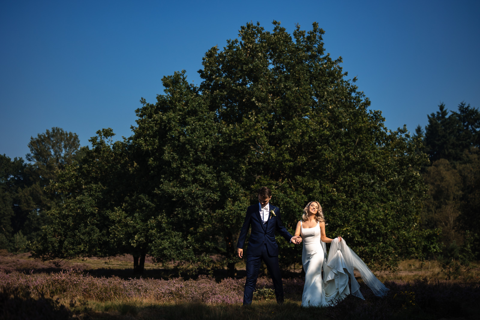 Herfst bruiloft Kasteel Hoekelum bruidspaar wandelt samen over de heide