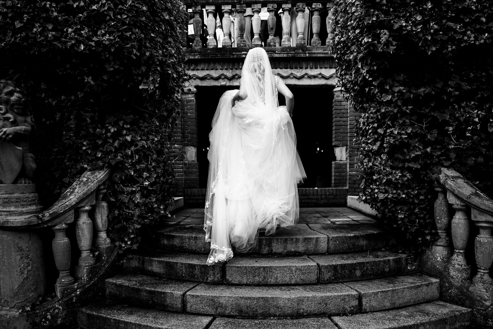 bruid tilt haar jurk op terwijl ze de trap op loopt bij Kasteel de Hooge Vuursche