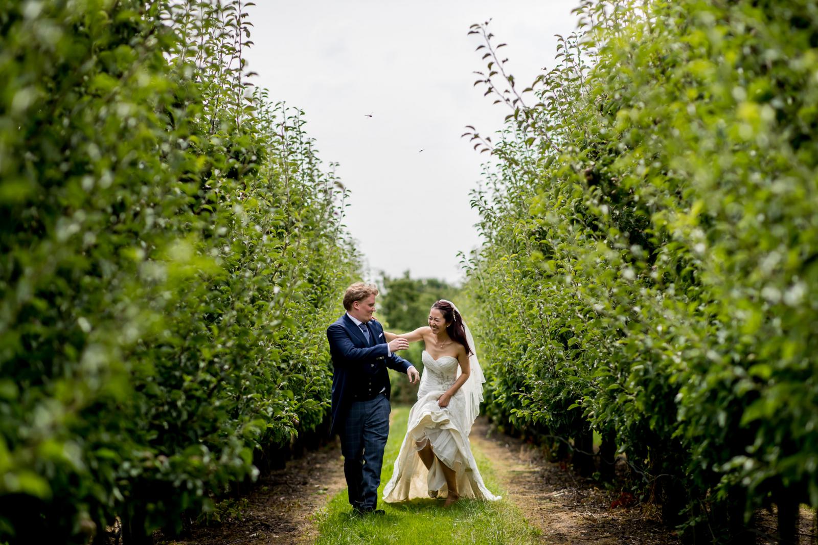 Bruidspaar rent samen door boomgaard tijdens fotoshoot kasteel wijenburg echteld 