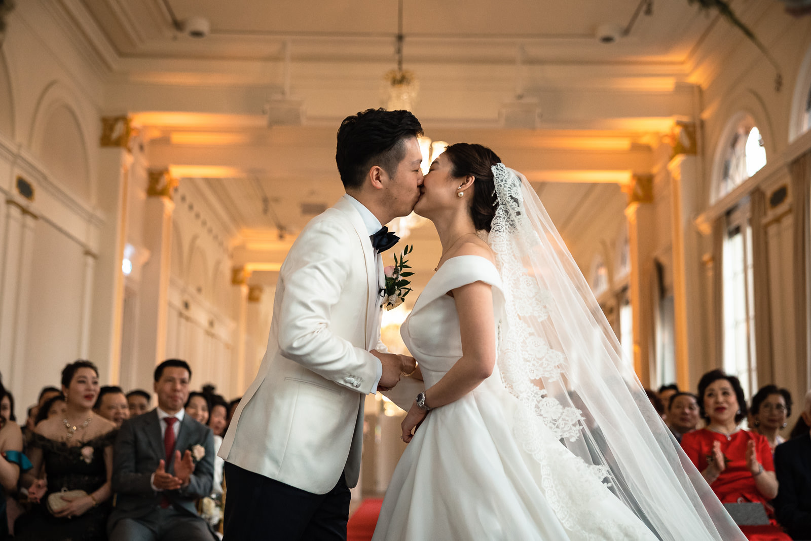 First kiss Chinees bruidspaar tijdens trouwceremonie Chinese bruidegom komt met moeder aanlopen voor de ceremonie Trouwfotograaf Rotterdam Wereld Museum en Huis ter Duijn Noordwijk