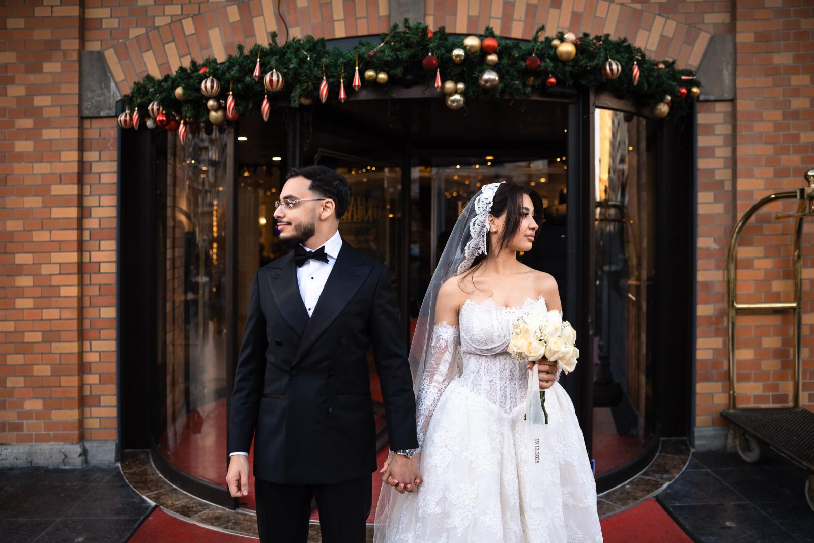Bride and groom holding hands in front of the Kurhaus entrance with Christmas decorations