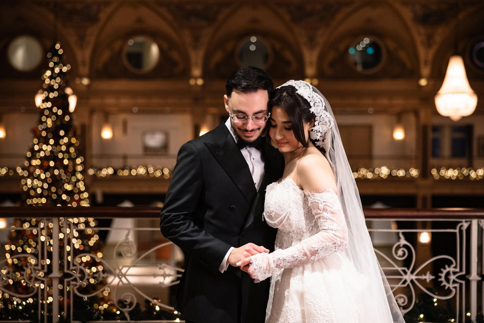 Bride and groom sharing an intimate moment inside the Kurhaus, large Christmas tree in background