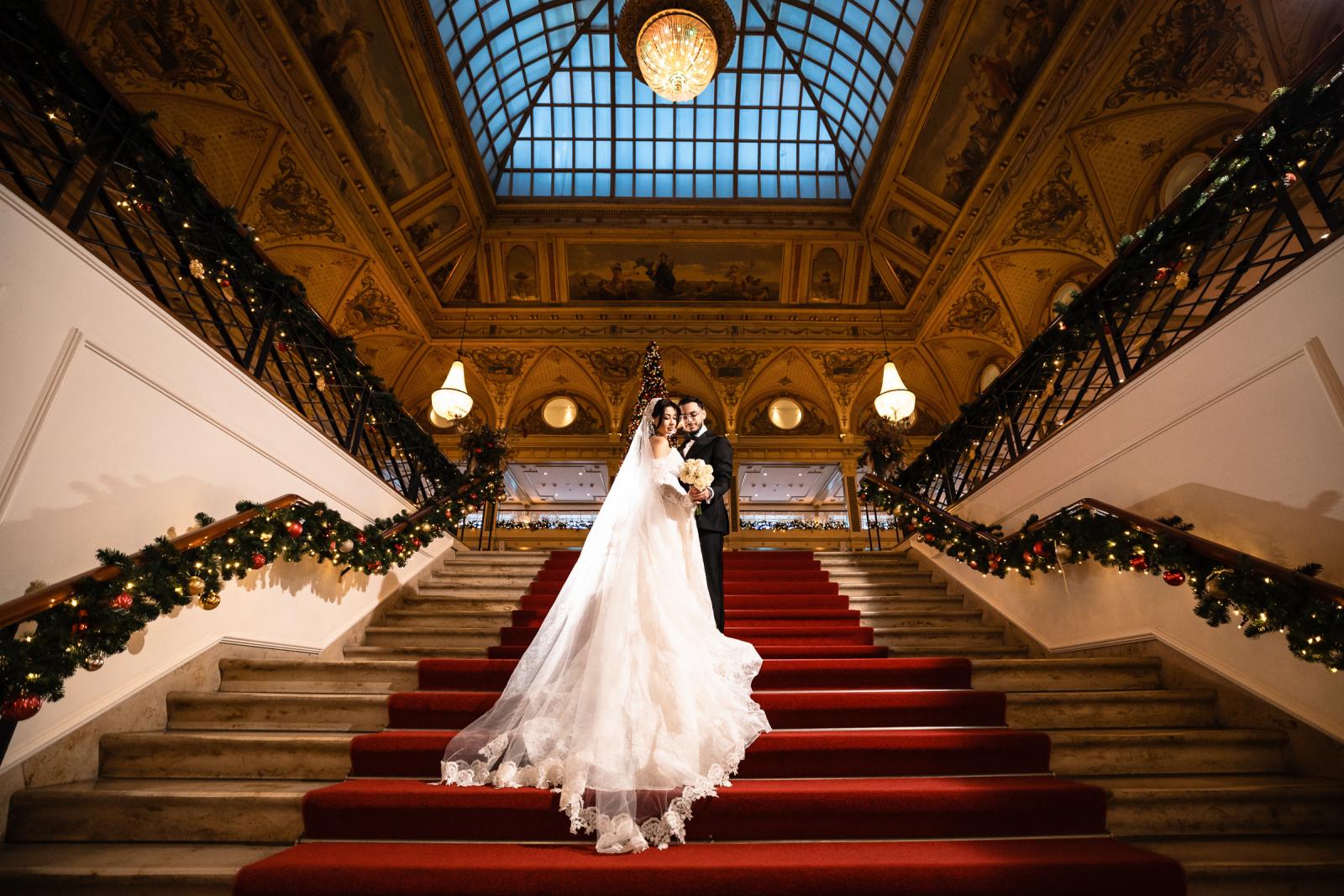 Bride and groom standing together on the Kurhaus staircase, dramatic train and golden decor