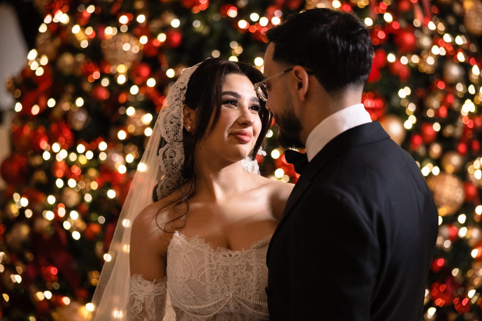 Bride and groom looking at each other lovingly, Christmas lights in the background