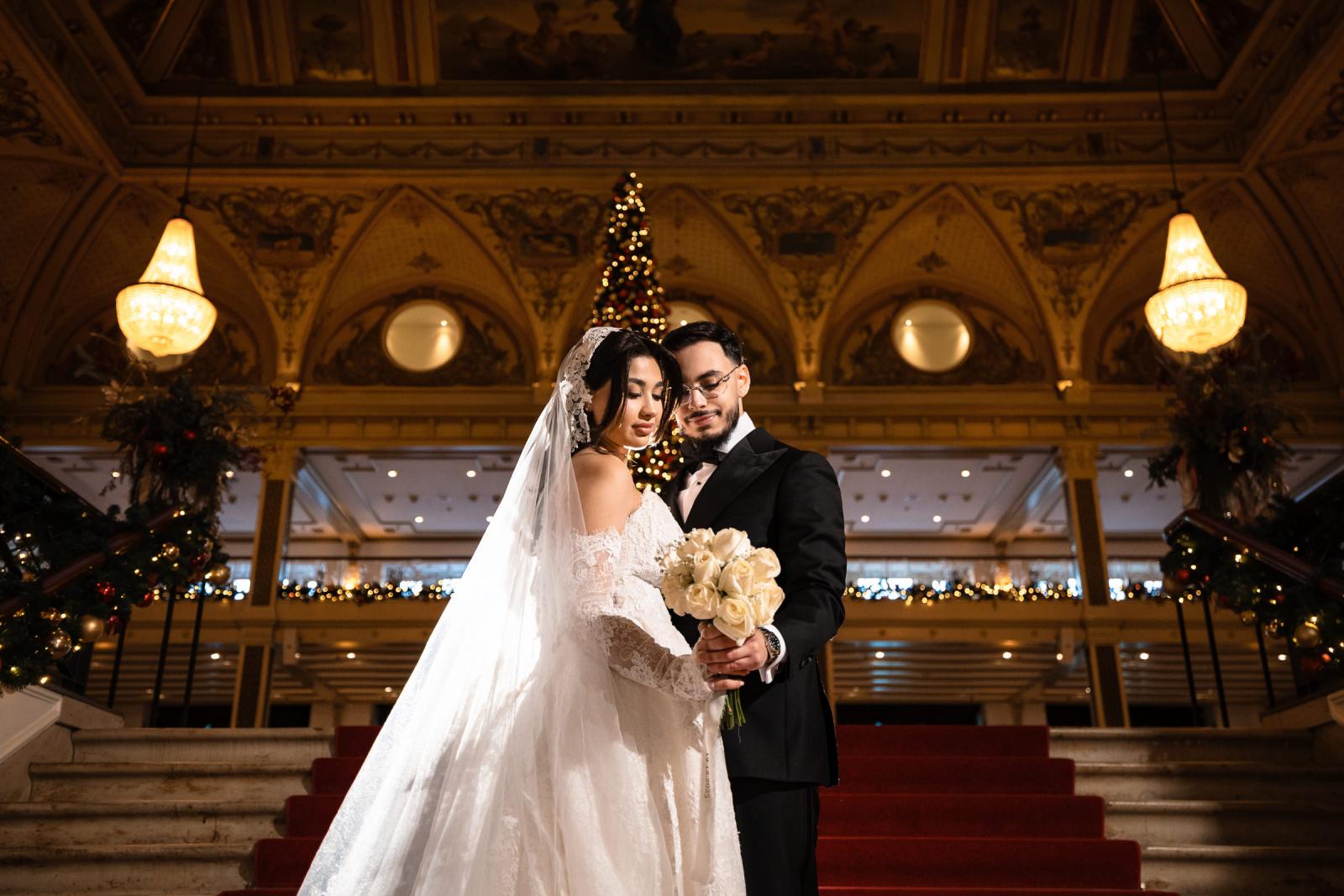 Couple embracing on the red stairs of the Kurhaus, Christmas tree centered behind them
