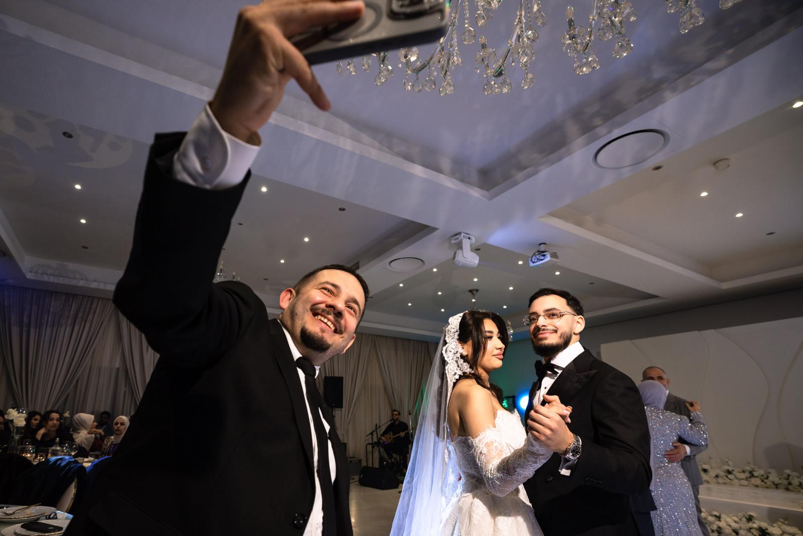 A guest taking a selfie with the bride and groom during their first dance on the wedding night.