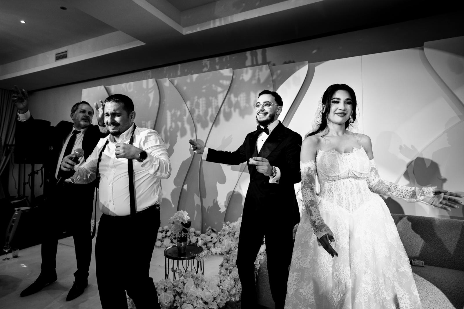 The groom, bride, and guests dancing on stage, captured in black and white.